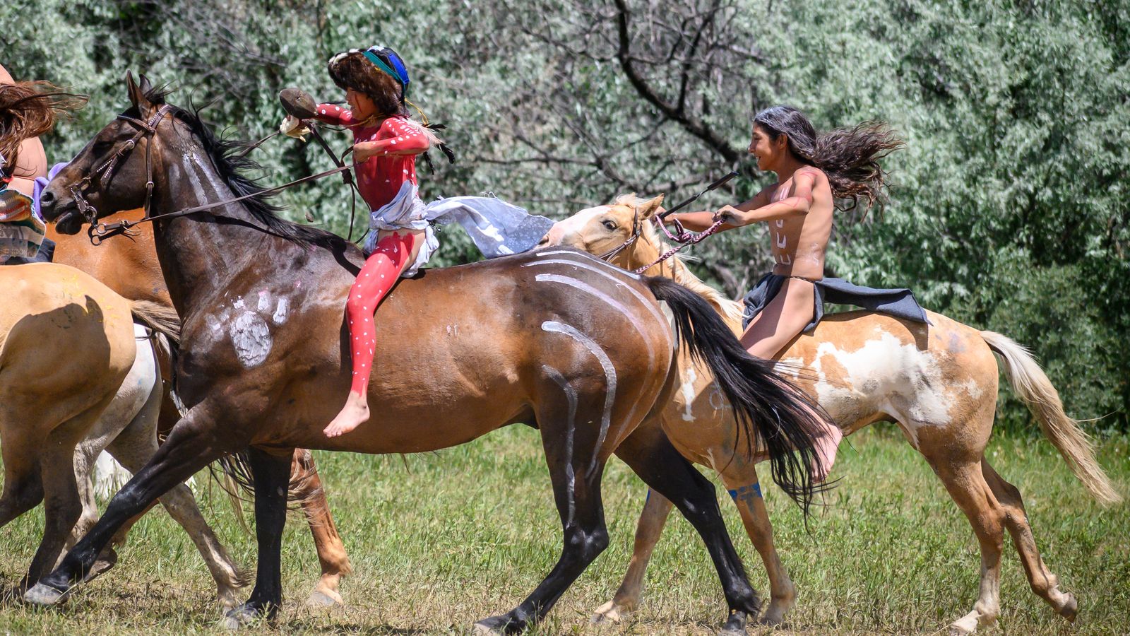 Tuff NotAfraid, red paint, rides for the first time as a warrior in the Real Bird Reenactment. The past two years his grandpa, Yoyo NotAfraid, would take him to work as an outrider.