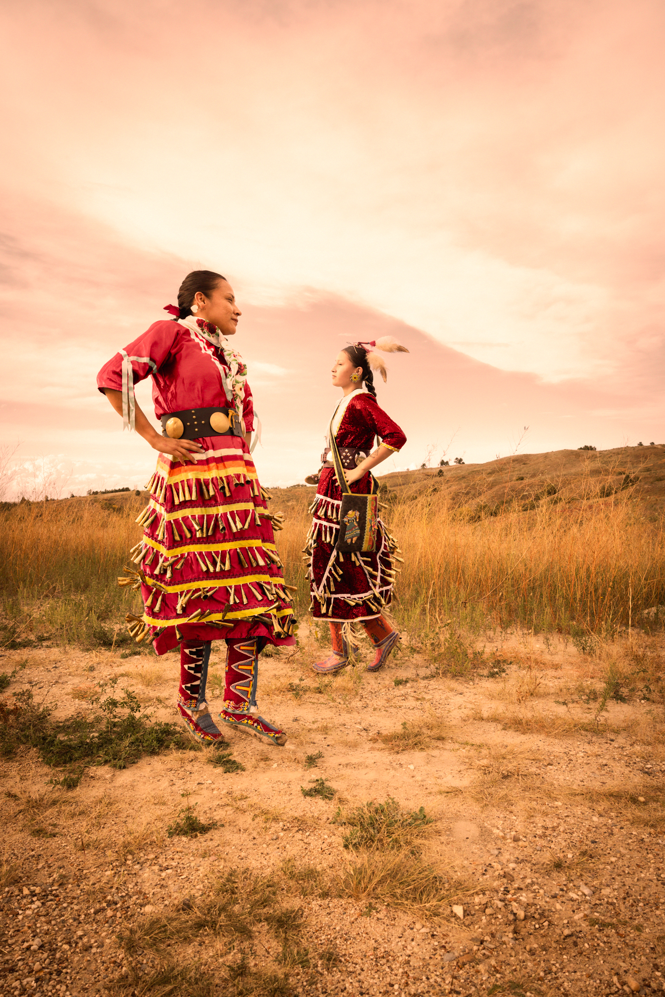 Lakota dancers Regina Makes Room for Them and her daughter Lesleen "Daye" Makes Room for Them wear red jingle dresses which signifies Missing and Murdered Indigenous Women.
