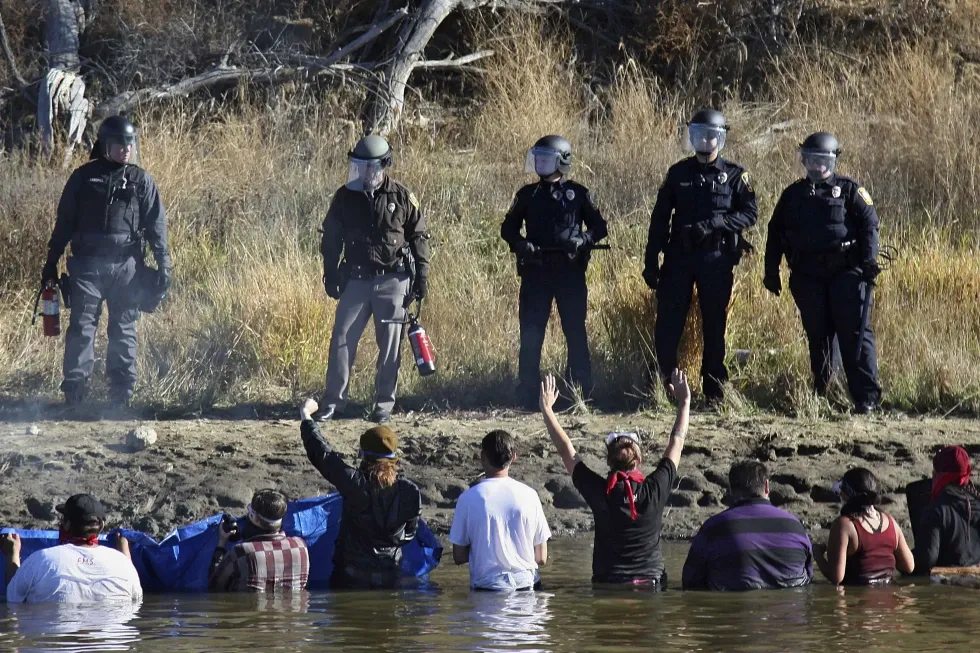 Protestors demonstrating against the expansion of the Dakota Access Pipeline wade in cold creek waters confronting local police, near Cannon Ball, N.D., Nov. 2, 2016. (John L. Mone/AP)