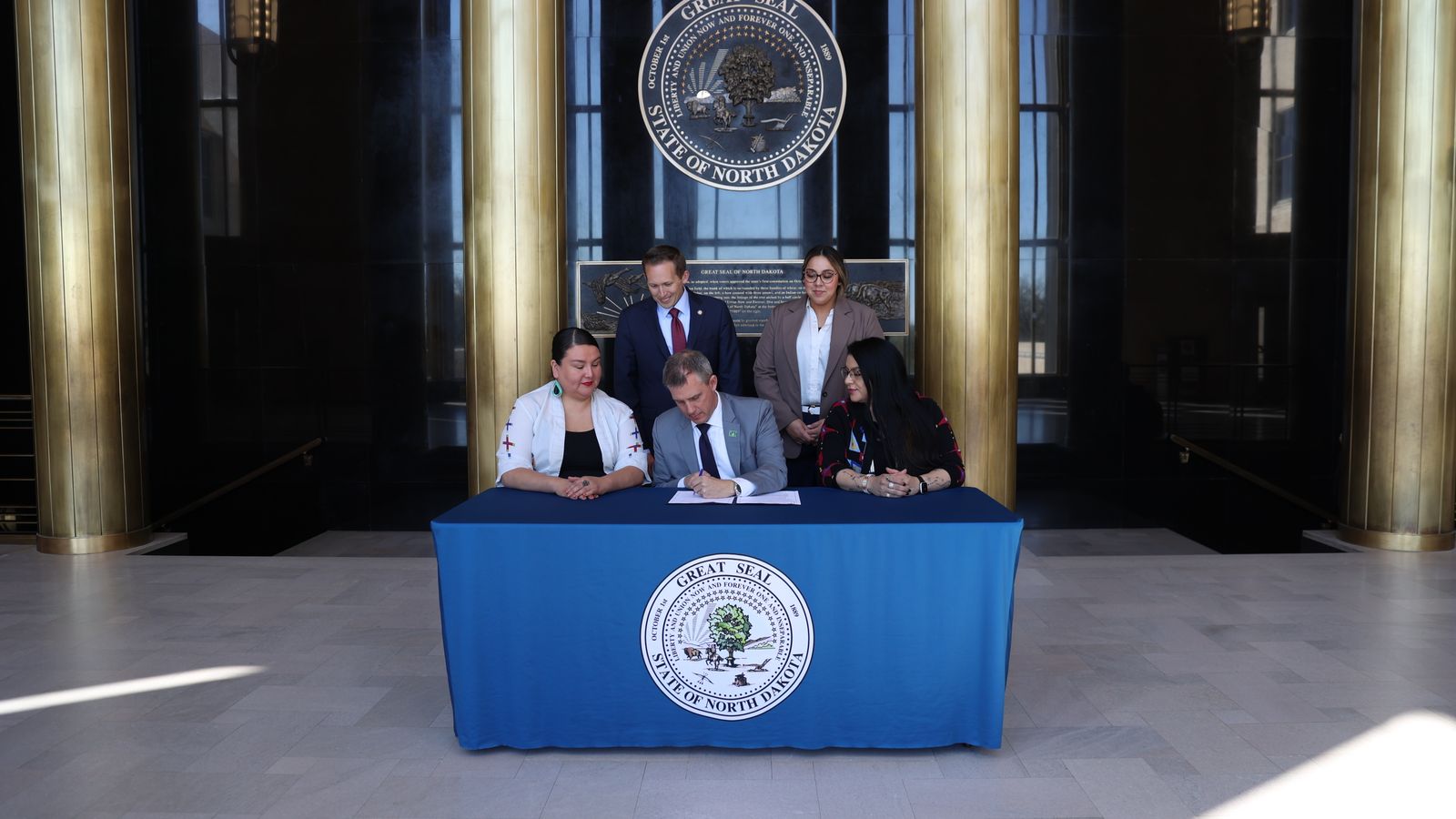 North Dakota Governor Kelly Armstrong signs HB 1535 into law on May 2, flanked by the bill’s sponsor, state. Rep. Jayme Davis on the left, and state Rep. Colette Brown on the right. Behind them are House Minority Leader Zach Ista and House Minority Office Assistant Shayla Davis. (Photo credit: North Dakota’s Governor’s Office)