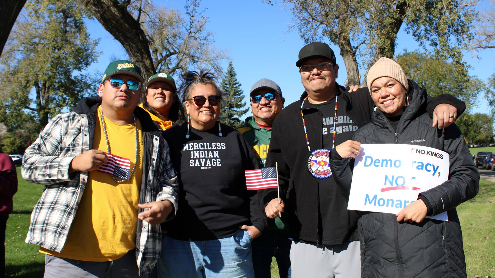Standing Rock Sioux Tribe citizens Peter Taken Alive, Summer Swimmer, Juliana White Bull, Crawford Taken Alive and Jonas Taken Alive and Umonhon Tribe of Nebraska citizen Lillian Taken Alive, stand together on the lawn of the state capitol at the “No Kings” rally. White Bull wore a shirt that said “Merciless Indian Savage,” Bismarck, North Dakota, Saturday, Oct. 18, 2025. (Buffalo’s Fire/Gabrielle Nelson)