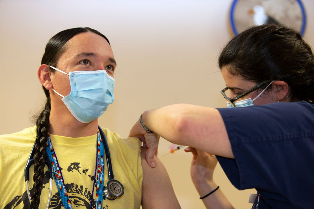 A clinical pharmacist with the Seattle Indian Health Board administers a shot of a COVID-19 vaccine in 2020. Tribal organizations, including health care clinics, have been disrupted by recent cuts to federal funding and staffing. (Karen Ducey/Getty Images)
